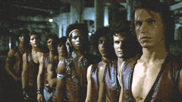 a group of men are standing in a row and one of them has a tattoo on his face