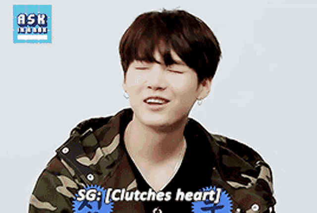 a young man wearing a camouflage jacket says sg : clutches heart