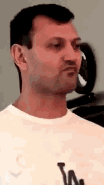 a man wearing a white la t-shirt looks at the camera
