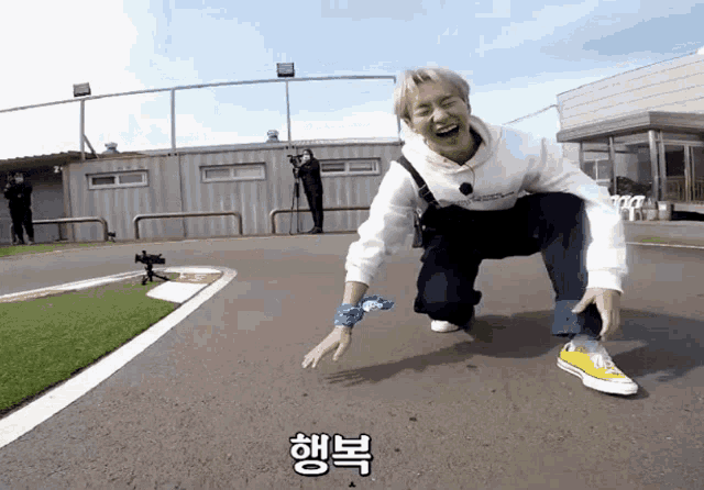 a man wearing a white hoodie and yellow shoes is kneeling on the ground