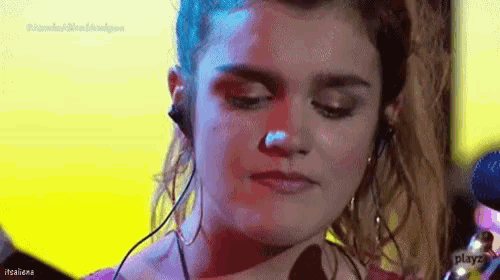 a woman wearing headphones is singing into a microphone on a stage .