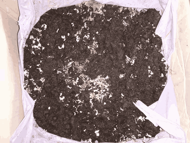 a pile of dirt with white spots on it in a white bag