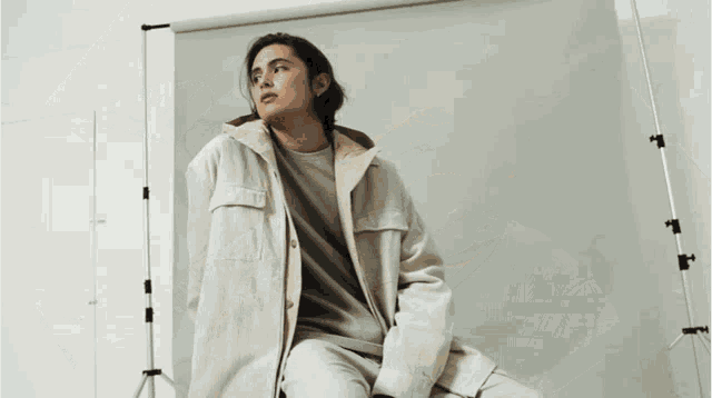 a woman with long hair is wearing a tan jacket