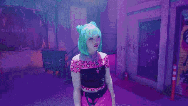 a girl with green hair is making a peace sign with her hands while standing in front of a purple background .
