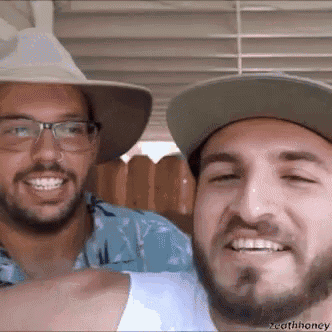 two men wearing hats and glasses are posing for a picture together .