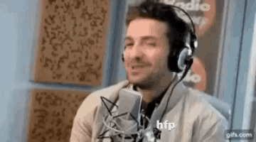 a man wearing headphones is talking into a microphone in a studio .