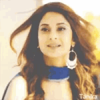a woman wearing a blue dress and earrings is smiling .