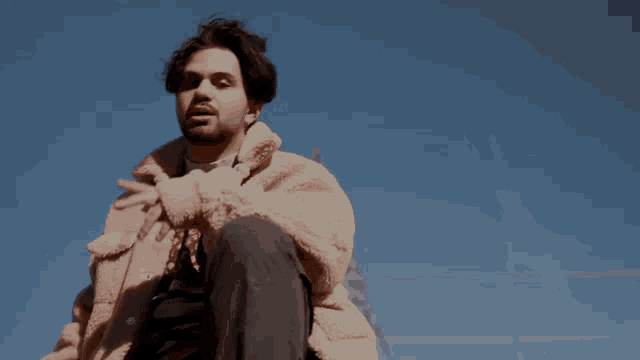 a man with a beard is wearing a pink jacket and black pants