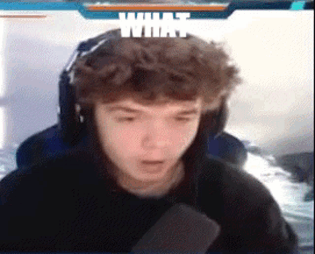 a young man wearing headphones is sitting in front of a screen with the word what on it .