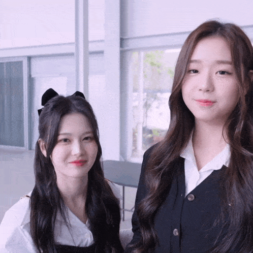 two girls are standing next to each other and smiling