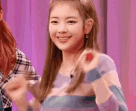 a close up of a woman giving a thumbs up sign while standing in front of a pink curtain .