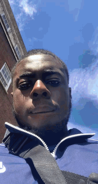 a man wearing a blue nike jacket is taking a selfie in front of a brick building
