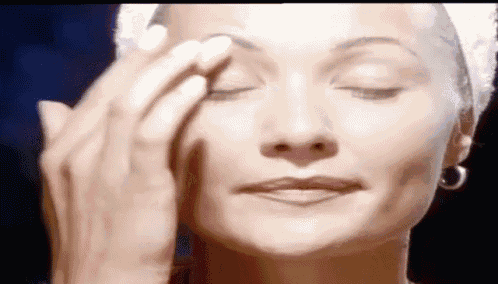 a woman with a towel wrapped around her head is applying makeup to her face