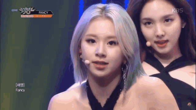 two women on a stage with fancy written on the screen behind them