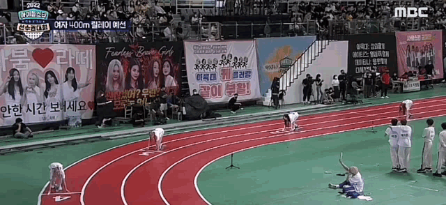 a group of people are running on a track in front of a crowd with a sign that says ' freedom beat girls ' on it