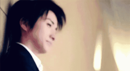 a man in a suit and tie is leaning against a wall .