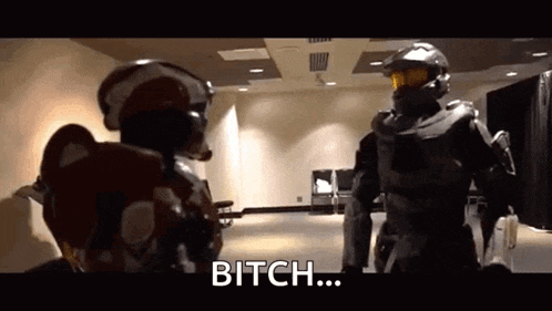 two soldiers in armor are standing next to each other in a room and talking to each other .