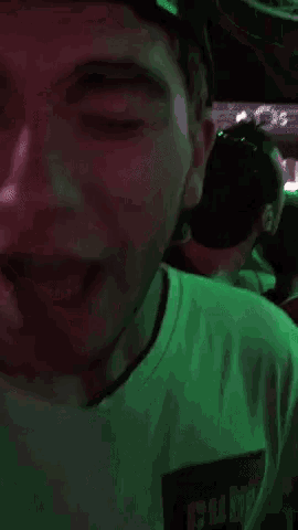 a man is laughing in a dark room with a green light behind him