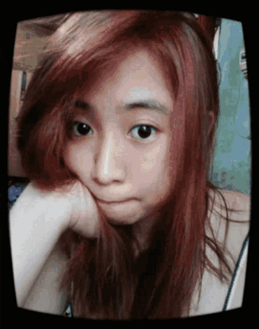 a girl with red hair is making a face with her hand