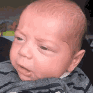 a close up of a baby 's face with a gray shirt on