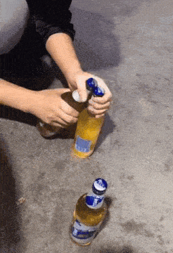 a person is opening a beer bottle with a blue cap