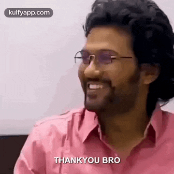 a man wearing glasses and a pink shirt is smiling and says `` thank you bro '' .