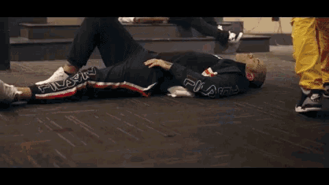 a man is laying on the floor wearing a fila jacket