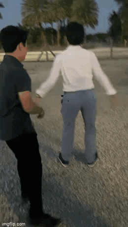 a man in a white shirt and blue pants is standing next to another man in a black shirt and black pants .