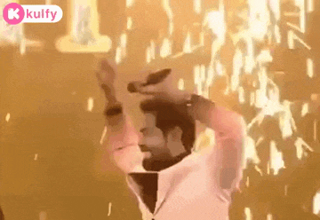 a man is holding a microphone in his hand while dancing in front of a crowd .