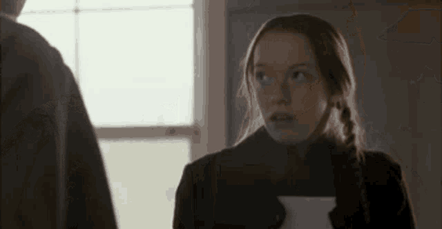 a woman is holding a piece of paper and looking up at a man .