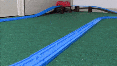 a toy train is going down a track with a red bridge