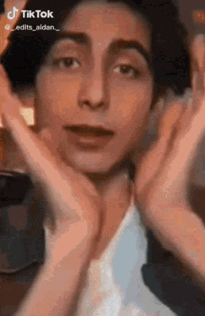 a close up of a person 's face with their hands in front of their face .