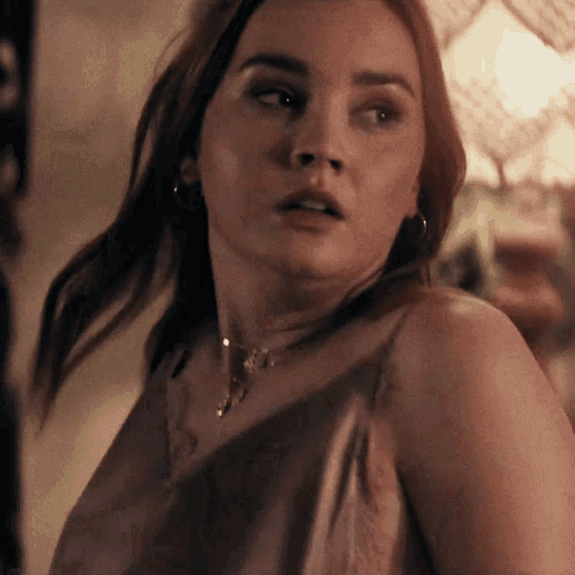 a close up of a woman 's face wearing a necklace and earrings