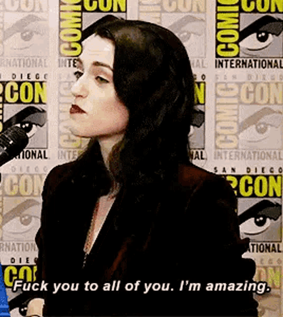 a woman is talking into a microphone at a comic con .