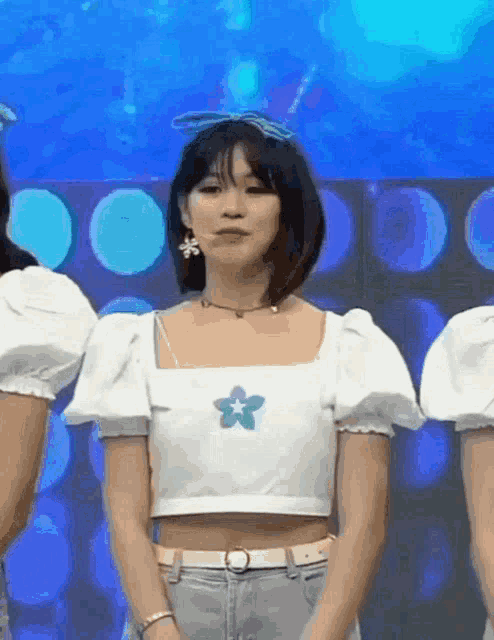 a girl wearing a white crop top with a blue flower on it