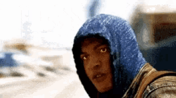 a man is wearing a blue hoodie and looking at the camera .