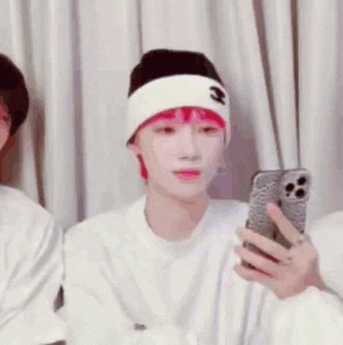 a person with red hair is looking at a cell phone while wearing a white headband .