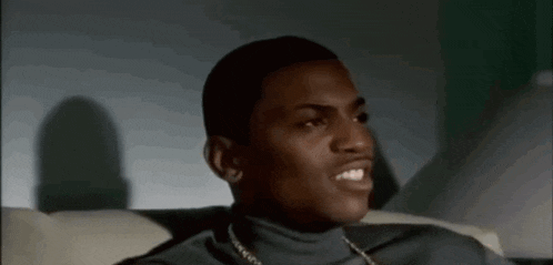 a man wearing a turtleneck and a chain is smiling while sitting on a couch .
