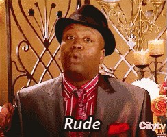 a man in a suit and hat says rude in front of candles