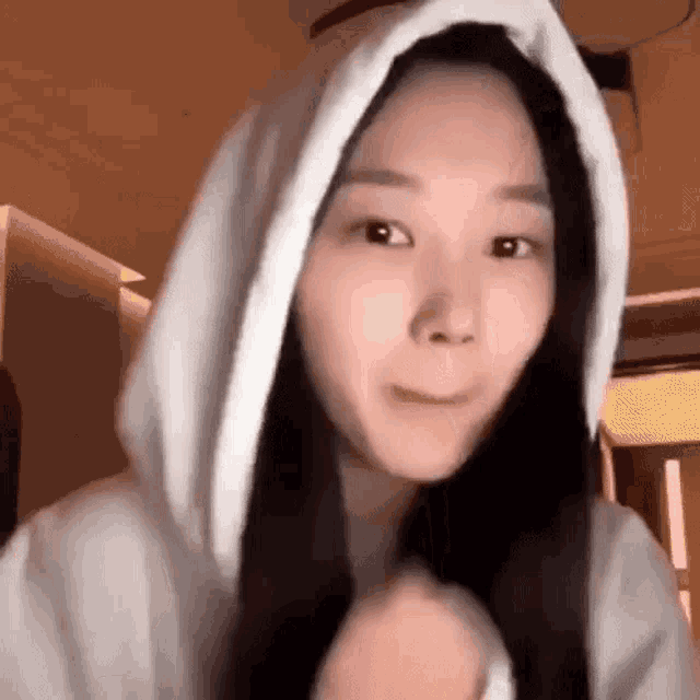 a woman wearing a white hoodie is making a face .