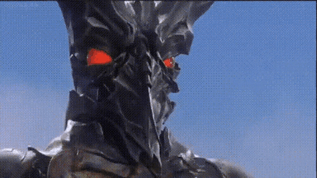 a close up of a monster with red eyes against a blue sky