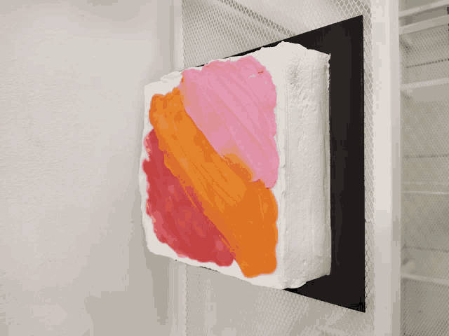 a pink and orange painting on a white block