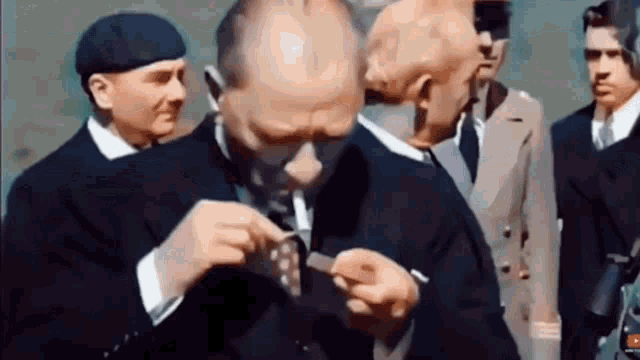 a group of men are standing around a man in a suit and tie .