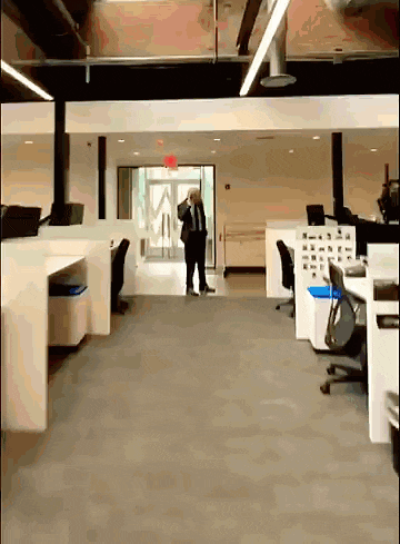 a man in a suit and tie is standing in an empty office talking on a cell phone