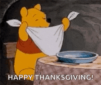 winnie the pooh is sitting at a table with a towel around his neck and a bowl of water .