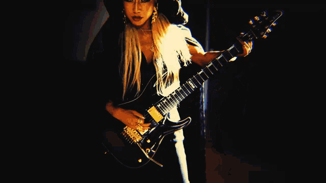 a woman with long blonde hair is playing a guitar