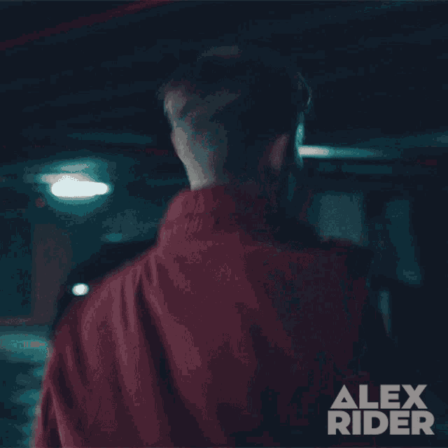 a young man in a red jacket with alex rider written on the bottom right