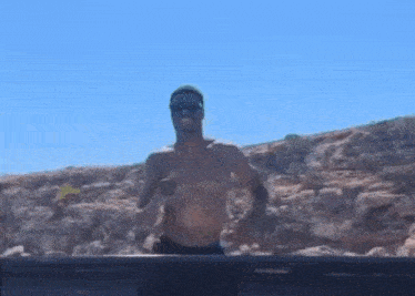 a man without a shirt is running on a rocky hillside .