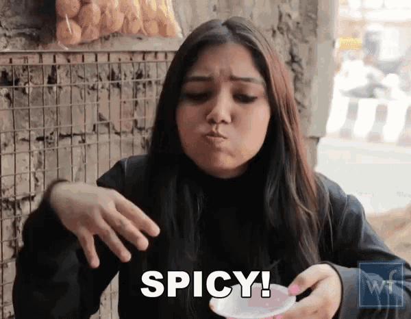a woman is eating something spicy and holding a cup