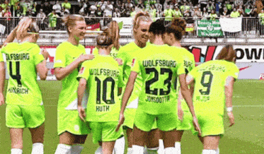 a group of female soccer players are huddled together with one wearing the number 23 on her back